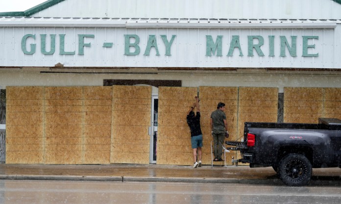 Doan Vu, izquierda, y Luan Nguyen, derecha, tapian las ventanas de su negocio en preparación para la llegada de la tormenta tropical Beryl, el domingo 7 de julio de 2024, en Palacios, Texas. (AP Foto/Eric Gay)