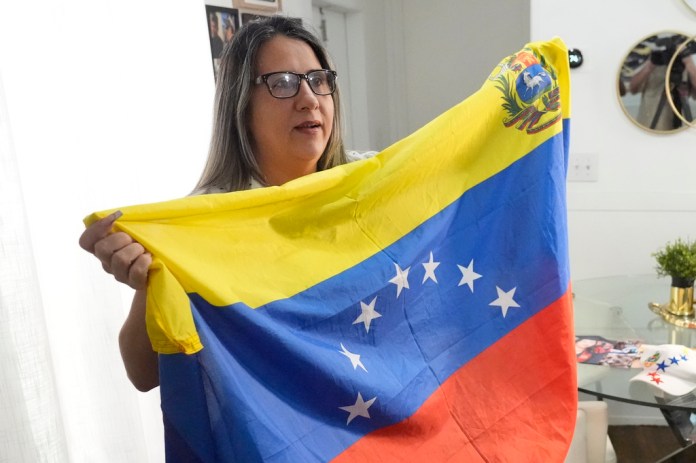 Yuly Macedo sostiene una bandera venezolana con siete estrellas que su hijo cuelga en su cuarto, la cual es distinta de la actual que tiene ocho estrellas y que estableció el entonces presidente Hugo Chávez. Macedo, quien dio una entrevista en Davie, Florida, el 11 de julio de 2024, dijo que siempre se opuso al gobierno de Nicolás Maduro. En abril de 2016 tomó un avión junto con su esposo y su hijo de 10 años rumbo a Miami, donde solicitó asilo político. (AP Foto/Wilfredo Lee)