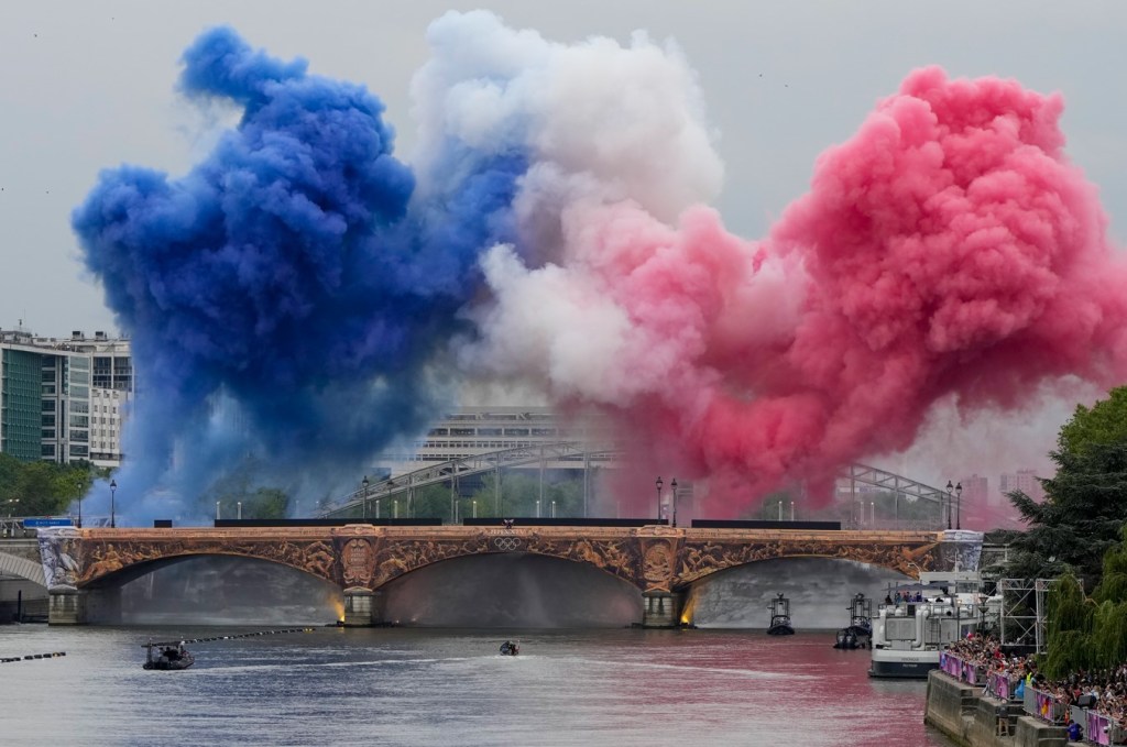 Humo con los colores de la bandera de Francia al dar comienzo la ceremonia de inauguración de los Juegos Olímpicos de París, el viernes 26 de julio de 2024. (AP Foto/Matthias Schrader)