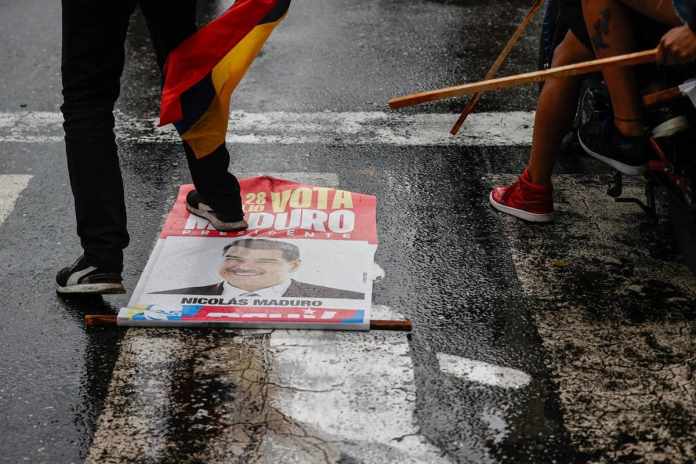 Una persona pisa un cartel con la imagen del presidente de Venezuela, Nicolás Maduro, durante una protesta por los resultados de las elecciones este lunes, en Caracas (Venezuela). EFE/ Henry Chirinos