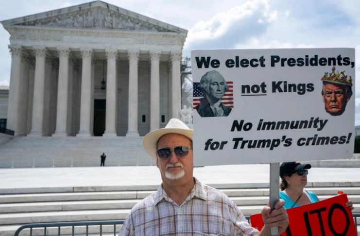 Un hombre muestra un mensaje en contra de la inmunidad de Donald Trump, afuera del Tribuanl Supremo de EE.UU., el 27 de junio de 2024, en Washington. EFE/Shawn Thew