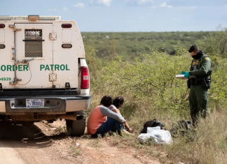 Un oficial de la Patrulla Fronteriza revisa los documentos de dos migrantes que recién cruzaron la frontera. Foto: CBP.