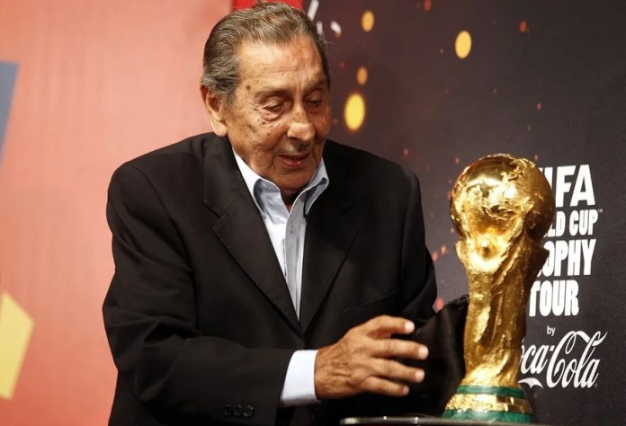 El exfutbolista uruguayo Alcides Ghiggi al tocar el trofeo del Mundial Brasil 2014, el 16 de enero de ese año, en Montevideo (Uruguay). EFE/Iván Franco