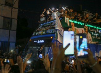 Imane Khelif, campeona olímpica de boxeo, saluda a la multitud desde un autobús, al desfilar por Tiaret, Argelia, el viernes 16 de agosto de 2024 (AP Foto/Anis Belghoul)