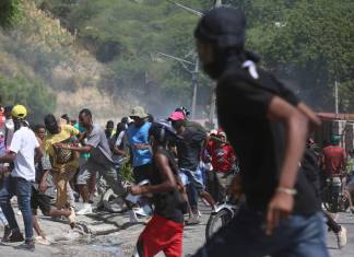 Un grupo de personas huye del gas lacrimógeno disparado por la policía para dispersar a los manifestantes que exigen a la policía y al primer ministro que actúen de inmediato contra las pandillas, en Puerto Príncipe, Haití, el lunes 19 de agosto de 2024. (AP Foto/Odelyn Joseph)