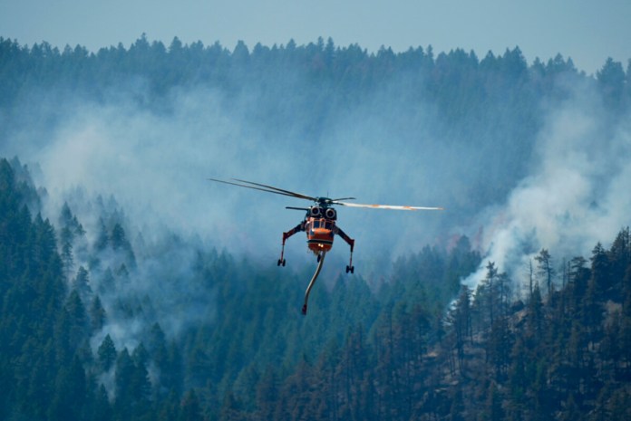 Un helicóptero se dirige a descargar agua sobre el incendio forestal Quarry que arde en las laderas cerca de Ken Caryl Ranch, el jueves, 1 de agosto 2024, al suroeste de Litteton, Colorado (Foto AP/ David Zalubowski).