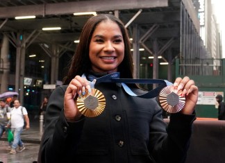 La gimnasta estadounidense y medallista olímpica Jordan Chiles muestra sus medallas tras el cierre del Nasdaq MarketSite, en Times Square, Nueva York, el jueves 8 de agosto de 2024. (AP Foto/Richard Drew)