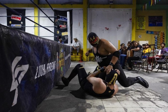 El luchador “Rey Kronos” golpea fuera del cuadrilatero a “discipulo”, durante la jornada de lucha libre de Planeta de Campeones en lGuatemala. EFE/David Toro