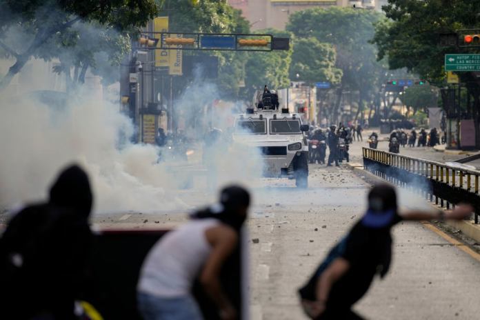 Manifestantes se enfrentan a la policía en las protestas contra los resultados de las elecciones que dieron por ganador a Nicolás Maduro, el día después de las votaciones en Caracas, Venezuela. (AP Foto/Matías Delacroix)