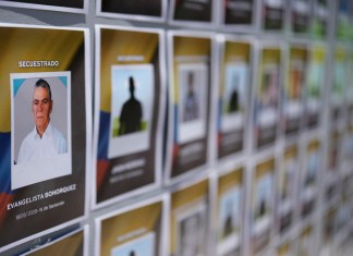 Fotos de personas secuestradas son expuestas en los exteriores de la Fiscalía General por activistas para conmemorar el Día Internacional de las Víctimas de Desapariciones Forzadas, en Bogotá, Colombia, el viernes 30 de agosto de 2024. (AP Foto/Fernando Vergara)