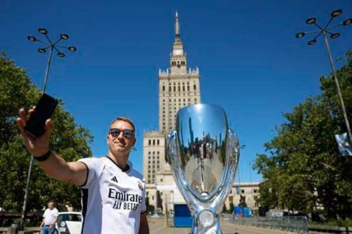 Aficionados del Real Madrid se hacen fotos junto una réplica del trofeo de la Supercopa junto a la Torre de la Ciencia de Varsovia poco antes del partido que disputarán el Real Madrid y el Atalanta en el estadio Narodowy de la capital polaca hoy 14 de agosto 2024. EFE/ Mariscal