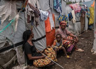Un grupo de personas en el campo de refugiados Don Bosco, mientras funcionarios de la Cruz Roja crean conciencia sobre el mpox en Goma, República Democrática del Congo, el jueves 22 de agosto de 2023. (AP Foto/Moses Sawasawa)