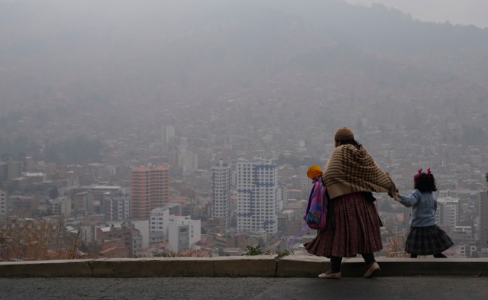 Archivo - Una mujer acompaña a su hija a la escuela en medio del humo de los incendios forestales en La Paz, Bolivia, el lunes 9 de septiembre de 2024. (AP Foto/Juan Karita, archivo)