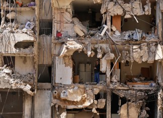 Un hombre observa a los rescatistas mientras revisan entre los escombros en busca de personas desaparecidas tras el ataque israelí del viernes sobre los suburbios del sur de Beirut, el lunes 23 de septiembre de 2024. (AP Foto/Hassan Ammar)