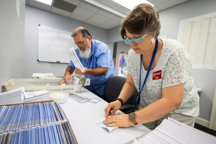 Dawn Stephens y Duane Taylor preparan boletas para votar que serán enviadas por correo postal, en la Junta Electoral del condado Mecklenburg, en Charlotte, Carolina del Norte, el 5 de septiembre de 2024. (AP Foto/Nell Redmond)