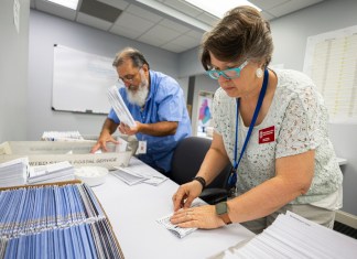 Dawn Stephens y Duane Taylor preparan boletas para votar que serán enviadas por correo postal, en la Junta Electoral del condado Mecklenburg, en Charlotte, Carolina del Norte, el 5 de septiembre de 2024. (AP Foto/Nell Redmond)