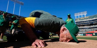 El fotógrafo del equipo de los Atléticos de Oakland, Michael Zagaris, besa el montículo del lanzador después de un partido de béisbol contra los Rangers de Texas en Oakland, California, el jueves 26 de septiembre de 2024. (AP Foto/Godofredo A. Vásquez)