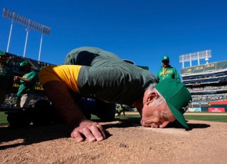 El fotógrafo del equipo de los Atléticos de Oakland, Michael Zagaris, besa el montículo del lanzador después de un partido de béisbol contra los Rangers de Texas en Oakland, California, el jueves 26 de septiembre de 2024. (AP Foto/Godofredo A. Vásquez)