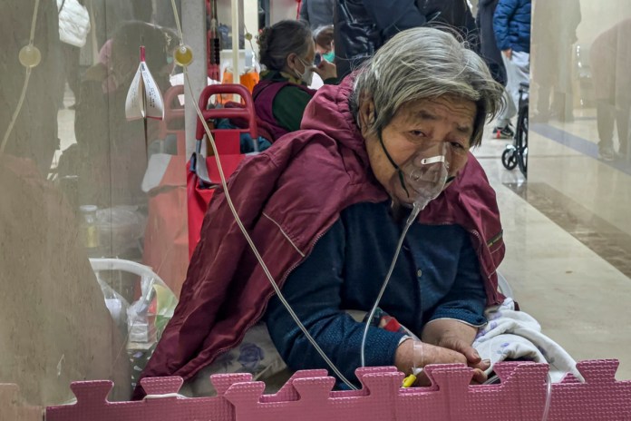 Una paciente de la tercera edad recibe una inyección por goteo intravenoso mientras usa un respirador en el corredor de una sala de emergencia en Beijing, el jueves 5 de enero de 2023. (AP Foto/Andy Wong, Archivo)