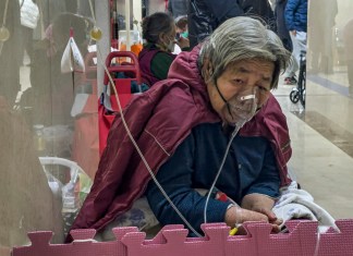 Una paciente de la tercera edad recibe una inyección por goteo intravenoso mientras usa un respirador en el corredor de una sala de emergencia en Beijing, el jueves 5 de enero de 2023. (AP Foto/Andy Wong, Archivo)