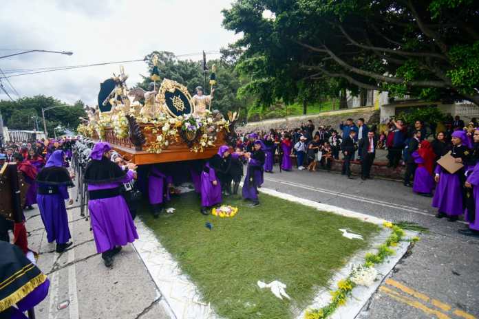 Hombres recorren las calles mientras llevan en hombros la imagen de Jesús de las Tres Potencias.