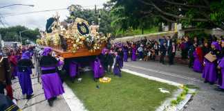 Hombres recorren las calles mientras llevan en hombros la imagen de Jesús de las Tres Potencias.