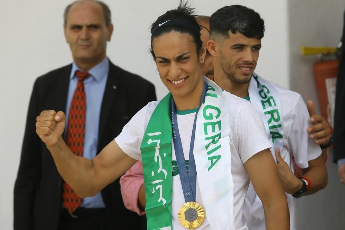 La medallista de oro en boxeo femenino de 66 kg, la argelina Imane Khelif, a la izquierda, y el medallista de bronce en los 800 metros masculinos, Djamel Sedjati, llegan después de los Juegos Olímpicos de Verano de 2024, el lunes 12 de agosto de 2024, en el aeropuerto de Argel, Argelia. (AP Foto/Anis Belghoul)