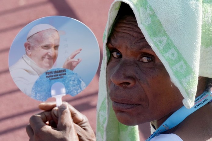 Una mujer utiliza un abanico y se protege del sol con una toalla mientras el papa Francisco celebra una misa en el estadio Sir John Guise, el domingo 8 de septiembre de 2024, en Puerto Moresby, Papúa Nueva Guinea. (Foto AP/Mark Baker)