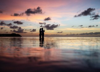 En esta imagen de archivo, dos turistas observan la puesta de sol en una popular playa en Tamuning, Guam, el 6 de mayo de 2019. Foto La Hora / AP