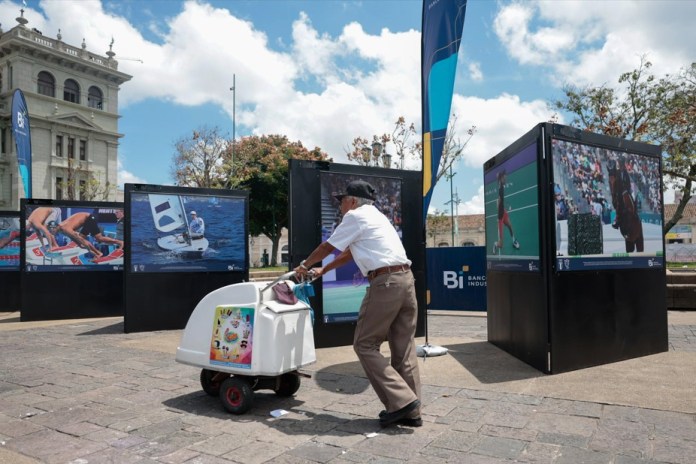 Un vendedor de helados recorre la exposición fotográfica sobre la participación de atletas guatemaltecos en los Juegos Olímpicos París 2024, este martes en la Plaza de la Constitución en la Ciudad de Guatemala 