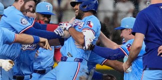 Marcus Semien (centro), de los Rangers de Texas, es felicitado por sus compañeros luego de conectar un sencillo que remolcó al dominicano Leody Taveras en el 9no episodio del juego de béisbol ante los Marineros de Seattle, el domingo 22 de septiembre de 2024, en Arlington, Texas. (AP Foto/LM Otero)