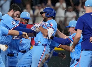 Marcus Semien (centro), de los Rangers de Texas, es felicitado por sus compañeros luego de conectar un sencillo que remolcó al dominicano Leody Taveras en el 9no episodio del juego de béisbol ante los Marineros de Seattle, el domingo 22 de septiembre de 2024, en Arlington, Texas. (AP Foto/LM Otero)