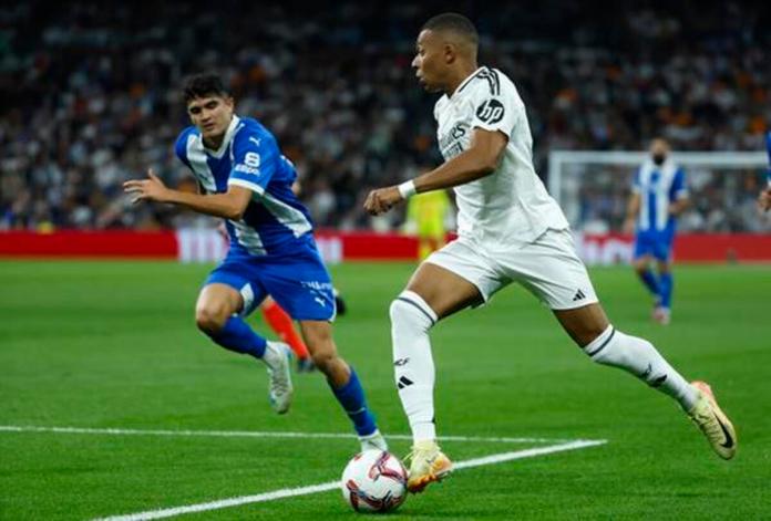 El delantero francés del Real Madrid, Kylian Mbappé (d), conduce el balón ante el defensor del Alavés durante el encuentro correspondiente a la séptima jornada de Laliga EA Sportsen el estadio Santiago Bernabéu, en Madrid. EFE / Juanjo Martín.