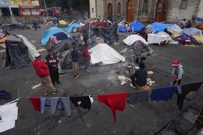 Migrantes se reúnen en un campamento instalado en la plaza de la parroquia de Santa Cruz y La Soledad, el 26 de diciembre de 2023, en el barrio de La Merced de Ciudad de México. (AP Foto/Marco Ugarte, Archivo)