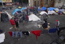 Migrantes se reúnen en un campamento instalado en la plaza de la parroquia de Santa Cruz y La Soledad, el 26 de diciembre de 2023, en el barrio de La Merced de Ciudad de México. (AP Foto/Marco Ugarte, Archivo)