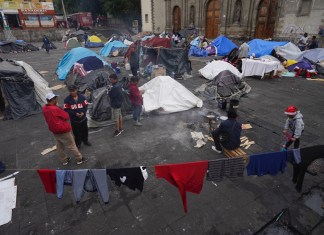 Migrantes se reúnen en un campamento instalado en la plaza de la parroquia de Santa Cruz y La Soledad, el 26 de diciembre de 2023, en el barrio de La Merced de Ciudad de México. (AP Foto/Marco Ugarte, Archivo)