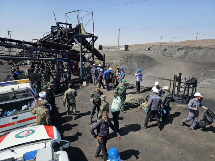 En esta foto publicada por la Sociedad de la Media Luna Roja Iraní, mineros y policías se ven junto a una mina de carbón donde una fuga de metano provocó una explosión el sábado en Tabas, unos 540 kilómetros (335 millas) al sureste de la capital, Teherán, Irán, el domingo 22 de septiembre de 2024. (Sociedad de la Media Luna Roja Iraní, via AP)