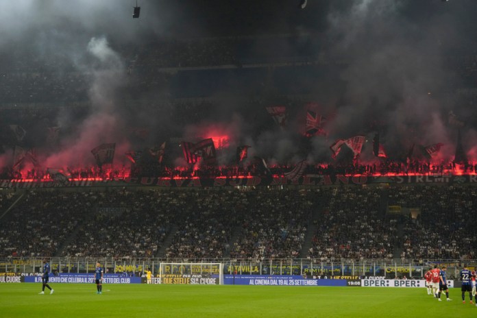 Hinchas del AC Milan encienden bengalas tras el gol de Christian Pulisic en el partido contra el Inter en el estadio San Siro de Milán, el domingo 22 de septiembre de 2024. (AP Foto/Luca Bruno)