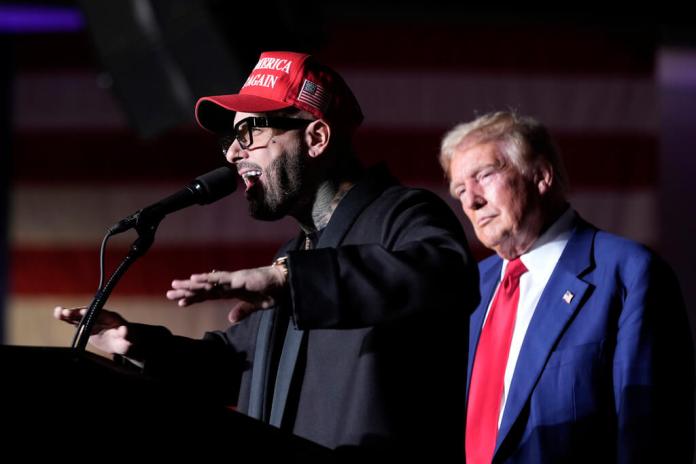 Nicky Jam habla mientras el candidato presidencial republicano, el expresidente Donald Trump, escucha durante un evento de campaña en el World Market Center, el viernes 13 de septiembre de 2024, en Las Vegas. (Foto AP/Alex Brandon)