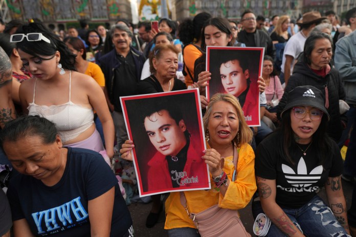 Fans de Juan Gabriel con afiches previo a una proyección de uno de sus conciertos en el Zócalo, la plaza principal de la Ciudad de México, el domingo 22 de septiembre de 2024. (Foto AP/Fernando Llano)