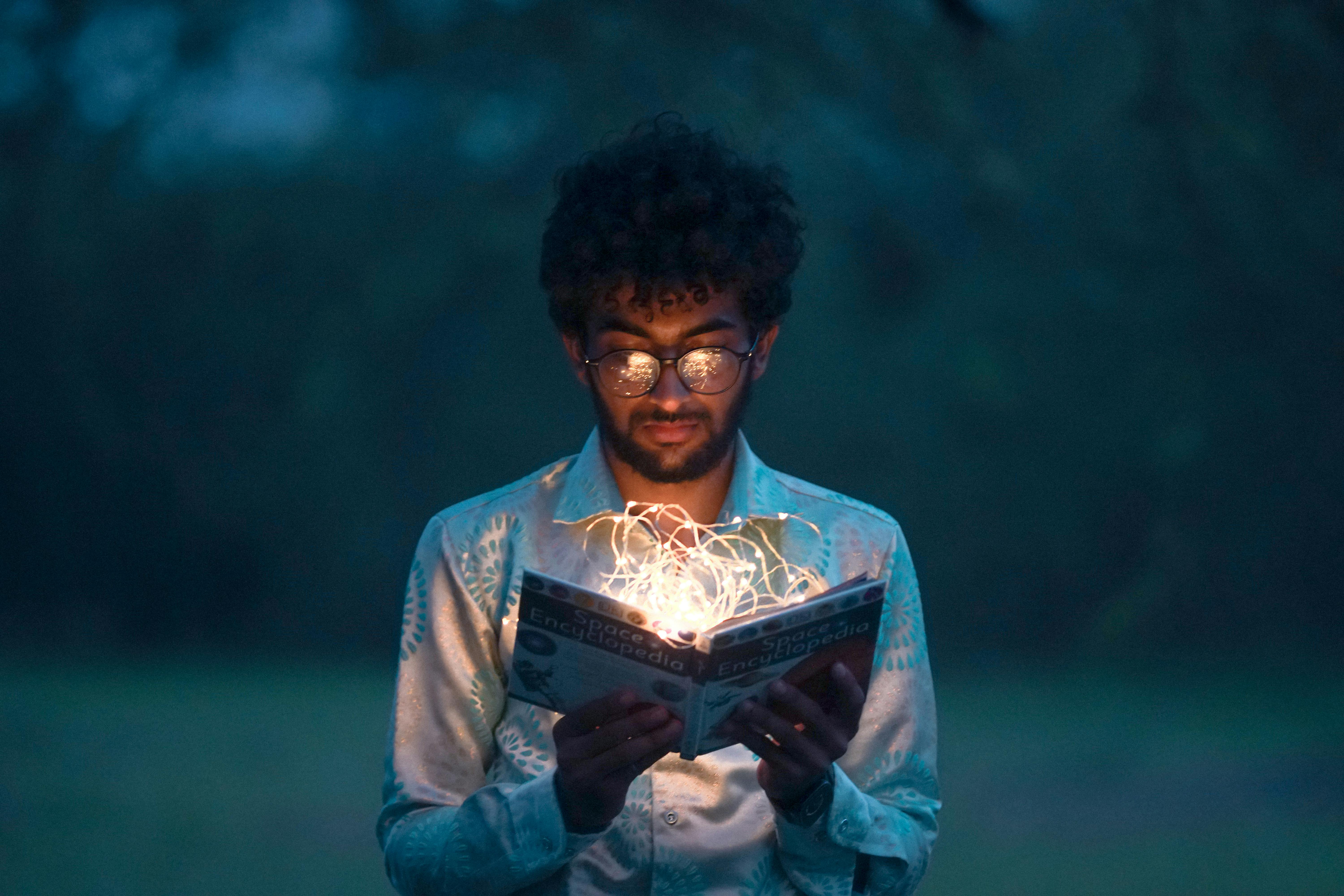 Hombre abriendo libro iluminado 