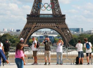Turistas se toman fotografías ante la Torre Eiffel, decorada con los aros de los Juegos Olímpicos este lunes en París