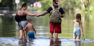 Dustin Holmes, segundo de derecha a izquierda, sostiene la mano de su novia, Hailey Morgan, mientras regresan a su vivienda inundada acompañados de sus hijos Aria Skye Hall, de 7 años, a la derecha, y Kyle Ross, de 4 años, tras el paso del huracán Helene, el 27 de septiembre de 2024, en Crystal River, Florida. (AP Foto/Phelan M. Ebenhack, Archivo)