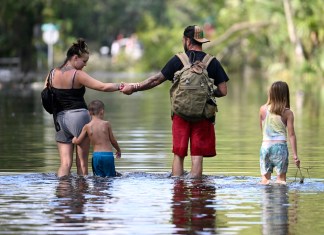 Dustin Holmes, segundo de derecha a izquierda, sostiene la mano de su novia, Hailey Morgan, mientras regresan a su vivienda inundada acompañados de sus hijos Aria Skye Hall, de 7 años, a la derecha, y Kyle Ross, de 4 años, tras el paso del huracán Helene, el 27 de septiembre de 2024, en Crystal River, Florida. (AP Foto/Phelan M. Ebenhack, Archivo)