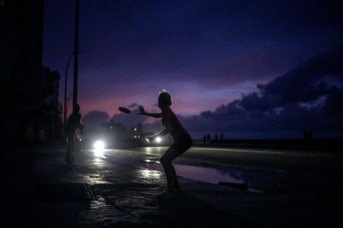 Una mujer se prepara para agarrar un frisbee durante el apagón masivo en el que derivó la caída en el funcionamiento de una de las mayores plantas termoeléctricas del país, en La Habana, Cuba, el viernes 18 de octubre de 2024. (AP Foto/Ramón Espinosa)