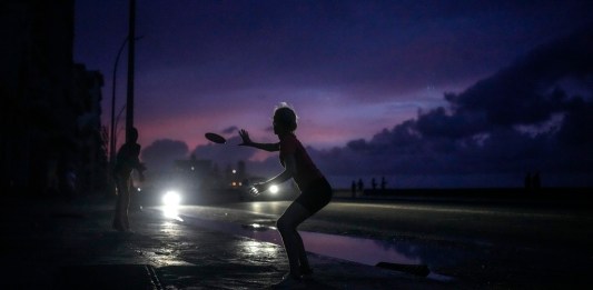 Una mujer se prepara para agarrar un frisbee durante el apagón masivo en el que derivó la caída en el funcionamiento de una de las mayores plantas termoeléctricas del país, en La Habana, Cuba, el viernes 18 de octubre de 2024. (AP Foto/Ramón Espinosa)