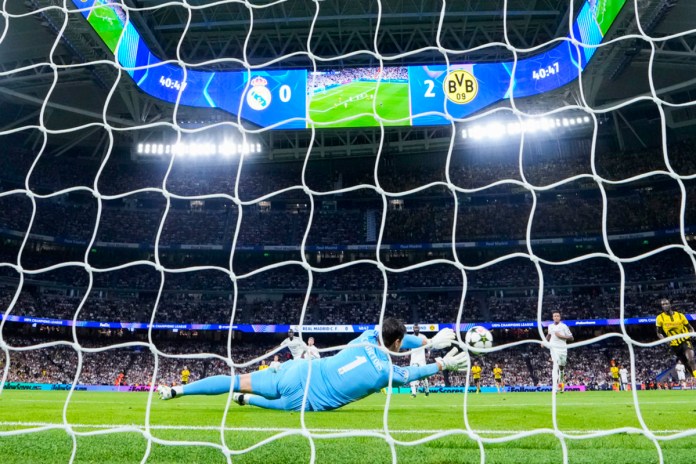 El portero del Real Madrid, Thibaut Courtois, bloquea un disparo durante el partido de la fase de apertura de la Liga de Campeones entre el Real Madrid y el Borussia Dortmund en el estadio Santiago Bernabéu de Madrid, el martes 22 de octubre de 2024. (AP Photo/Manu Fernandez)