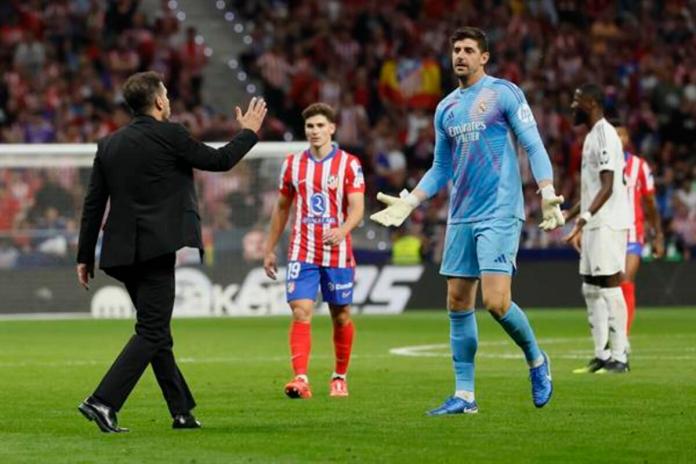 El portero del Real Madrid Thibaut Courtois (d) conversa con el entrenador del Atlético, Diego Simeone (i), durante el partido de la LaLiga EA Sports que Atlético de Madrid y Real Madrid en el estadio Civitas Metropolitano. EFE/Ballesteros