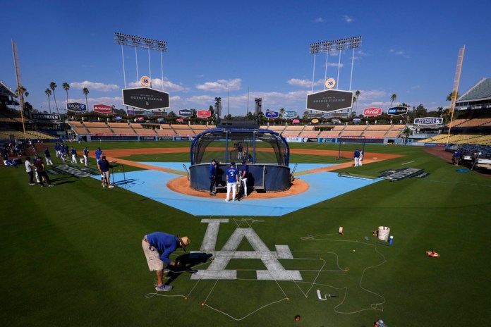 Un miembro del equipo de jardinería de los Dodgers de Los Ángeles pinta un logotipo en el campo antes de la práctica en preparación para el Juego 1 de una Serie Divisional de la Liga Nacional contra los Padres de San Diego, el jueves 3 de octubre de 2024, en Los Ángeles. (AP Foto/Mark J. Terrill)