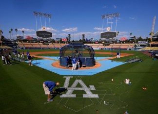 Un miembro del equipo de jardinería de los Dodgers de Los Ángeles pinta un logotipo en el campo antes de la práctica en preparación para el Juego 1 de una Serie Divisional de la Liga Nacional contra los Padres de San Diego, el jueves 3 de octubre de 2024, en Los Ángeles. (AP Foto/Mark J. Terrill)